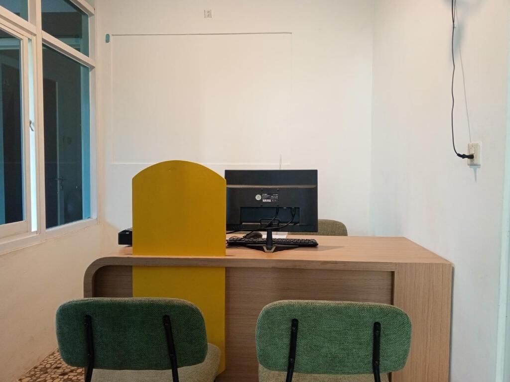 Une pièce comprenant un bureau, deux chaises, un ordinateur et une fenêtre.
