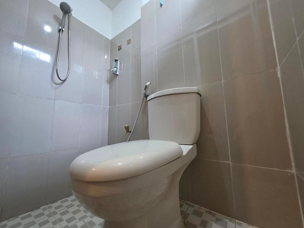 Een badkamer met toilet, douche en betegelde wanden.