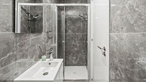A modern bathroom with a glass-enclosed shower, a white sink, and a mirror. - Noir Luxury Residence - Rooftop & Jacuzzi by Nomads (Limassol)