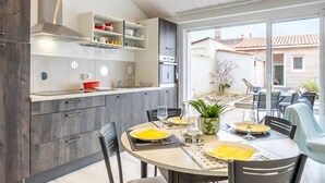 Una cocina moderna con electrodomésticos integrados, una zona de comedor con una mesa redonda y vistas al exterior.