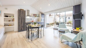 Una cocina moderna con comedor, un televisor montado en la pared y un gran ventanal corredizo que da a un patio exterior.