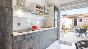 Una cocina moderna con gabinetes grises, una campana extractora de acero inoxidable y un comedor con mesa y sillas.