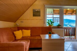 Un'accogliente stanza con soffitto in legno, un divano con cuscini gialli, un tavolino e una finestra vista all'esterno.