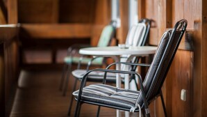 Interior em madeira com cadeiras de estrutura metálica e uma pequena mesa redonda.