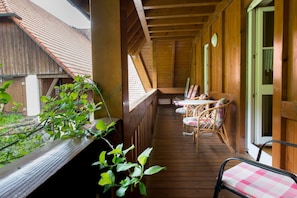 Eine Holzterrasse mit Esstisch und Stühlen, eine Holzwand und ein Fenster.