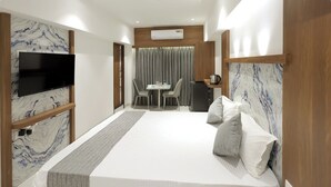 A modern hotel room with a large bed, a TV, a dining area, and a small kitchenette. - Host Inn Mumbai Airport (Mumbai)