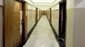 A hotel hallway with wooden doors, marble flooring, and recessed lighting. - Host Inn Mumbai Airport (Mumbai)