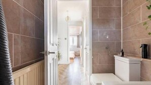 Et badeværelse med toilet, vask og bruseområde.