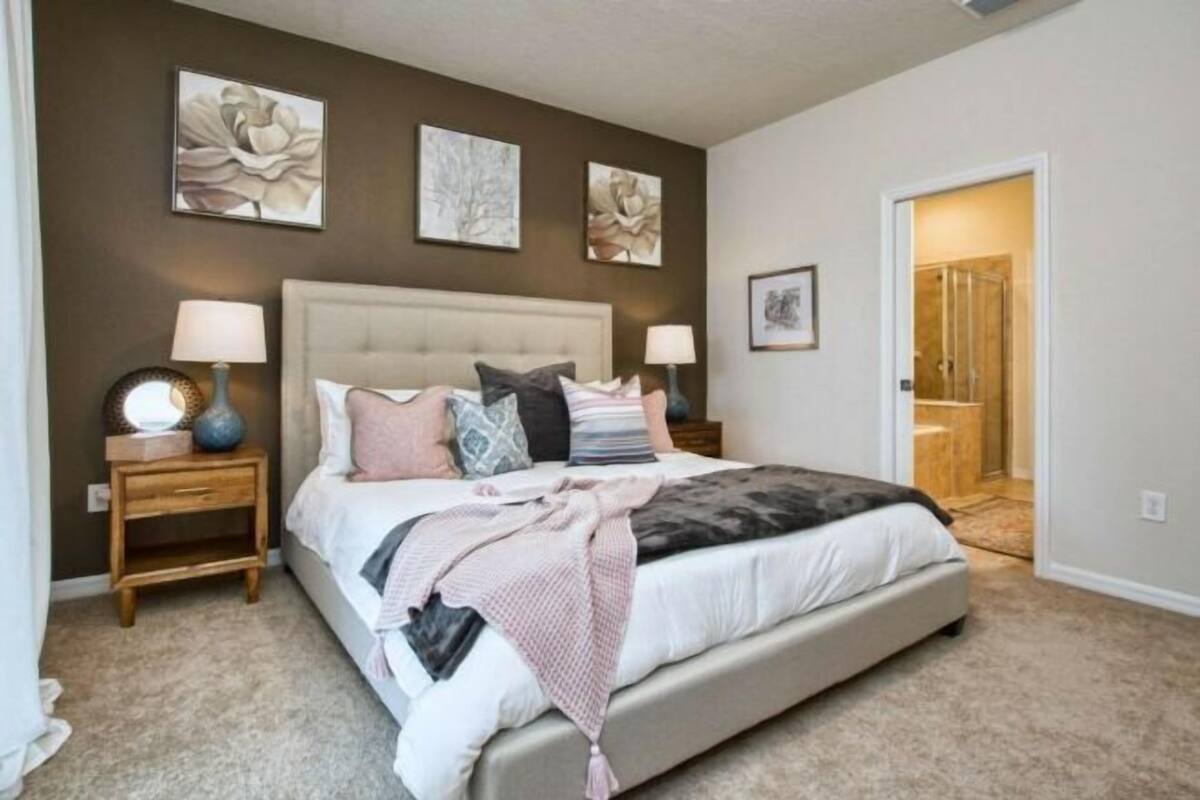 A bedroom with a large bed, two bedside tables, and three wall-mounted artworks.