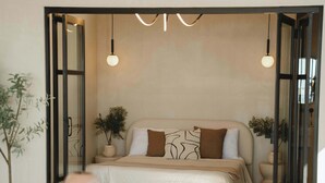 Une chambre moderne avec un grand lit, des tables de chevet et un coin repas comprenant une table et des chaises en bois.