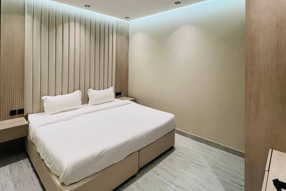 A modern bedroom with a large bed, built-in headboard, and recessed ceiling lighting.