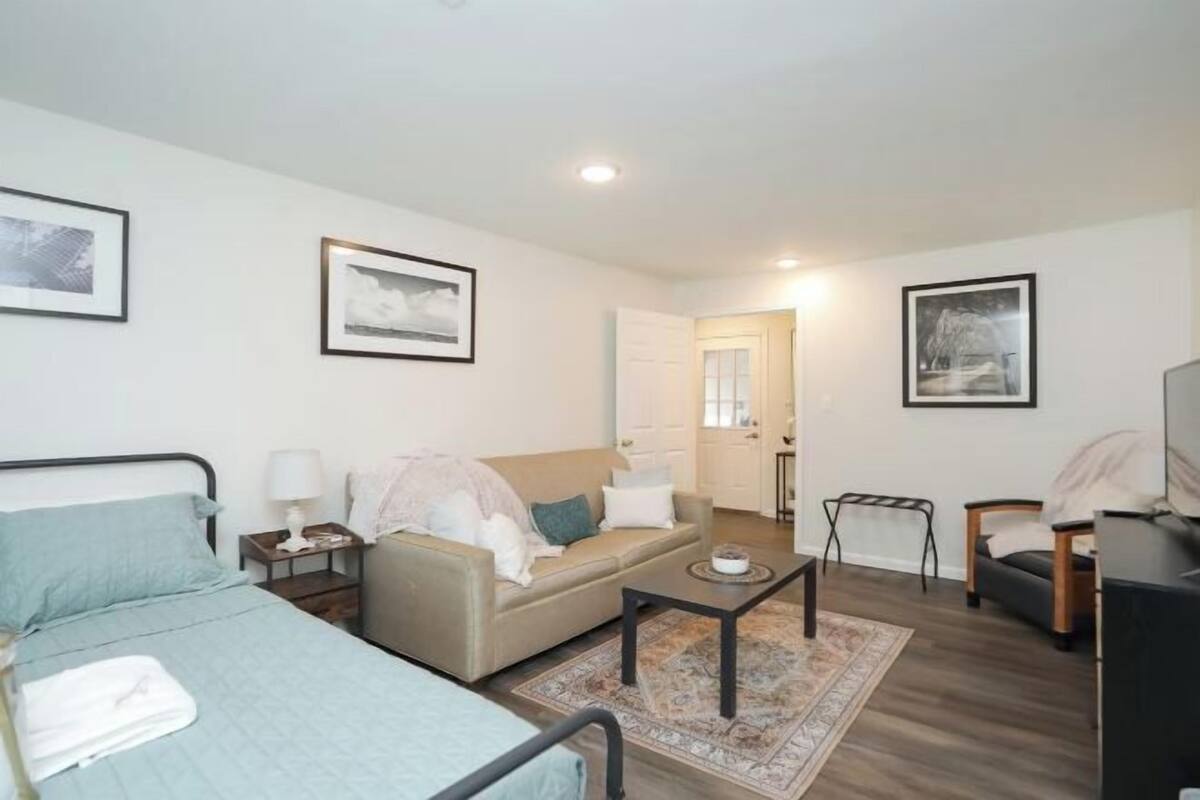 A bedroom with a bed, a sofa, a coffee table, and a TV.