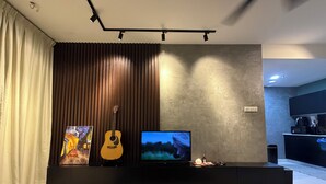 Un salón moderno con una televisión de pantalla plana, una guitarra y un cuadro en la pared.