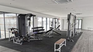 Un gimnasio con diferentes máquinas de ejercicio, mancuernas y un banco.