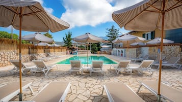 Una piscina al aire libre de temporada, sombrillas
