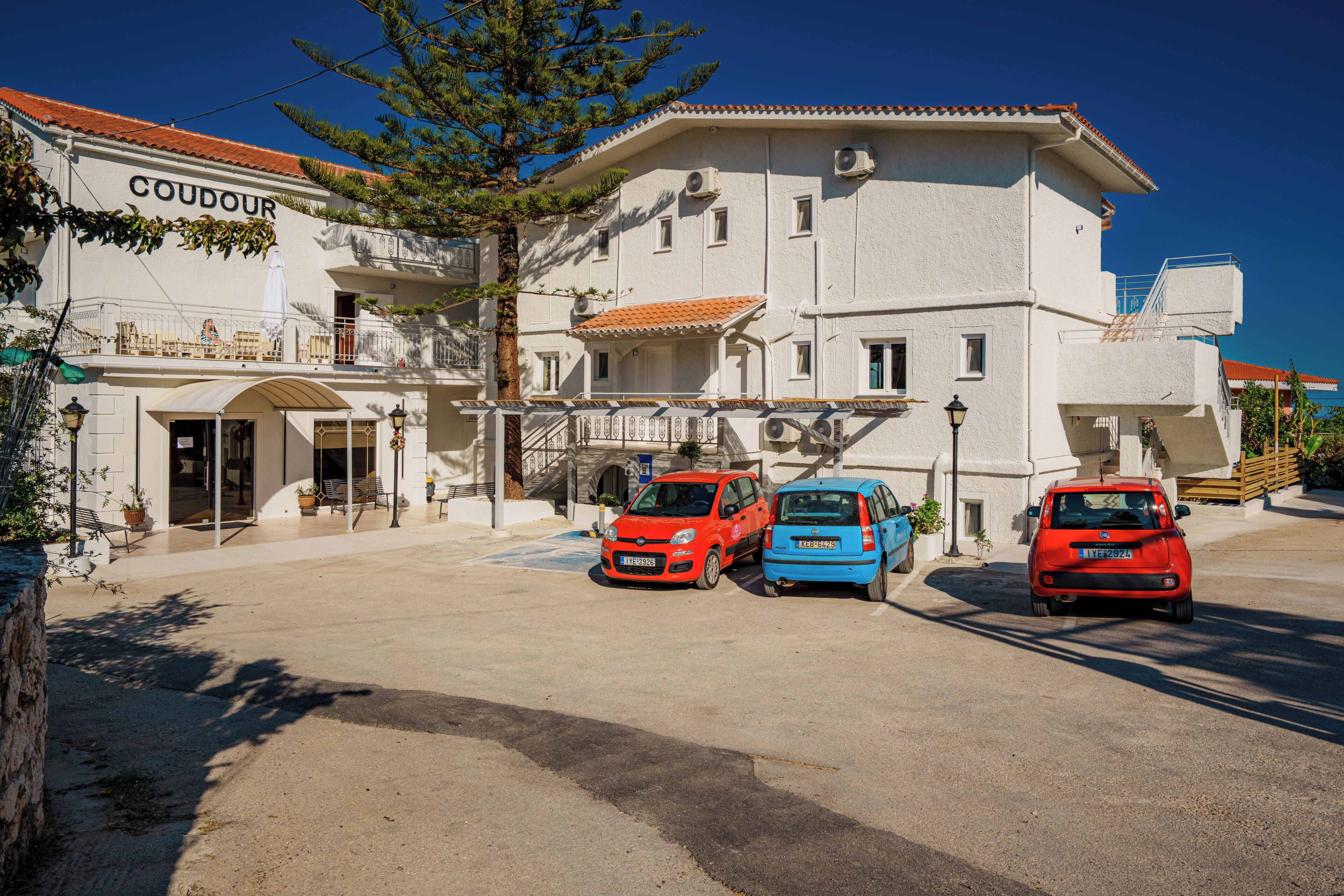 Un bâtiment avec une enseigne indiquant « COUDOUR » et deux voitures garées.