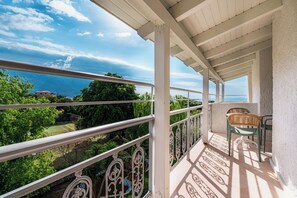A balcony with a view of the sea, a tennis court, and green chairs. - Coudour Boutique Hotel (Kefalonia)