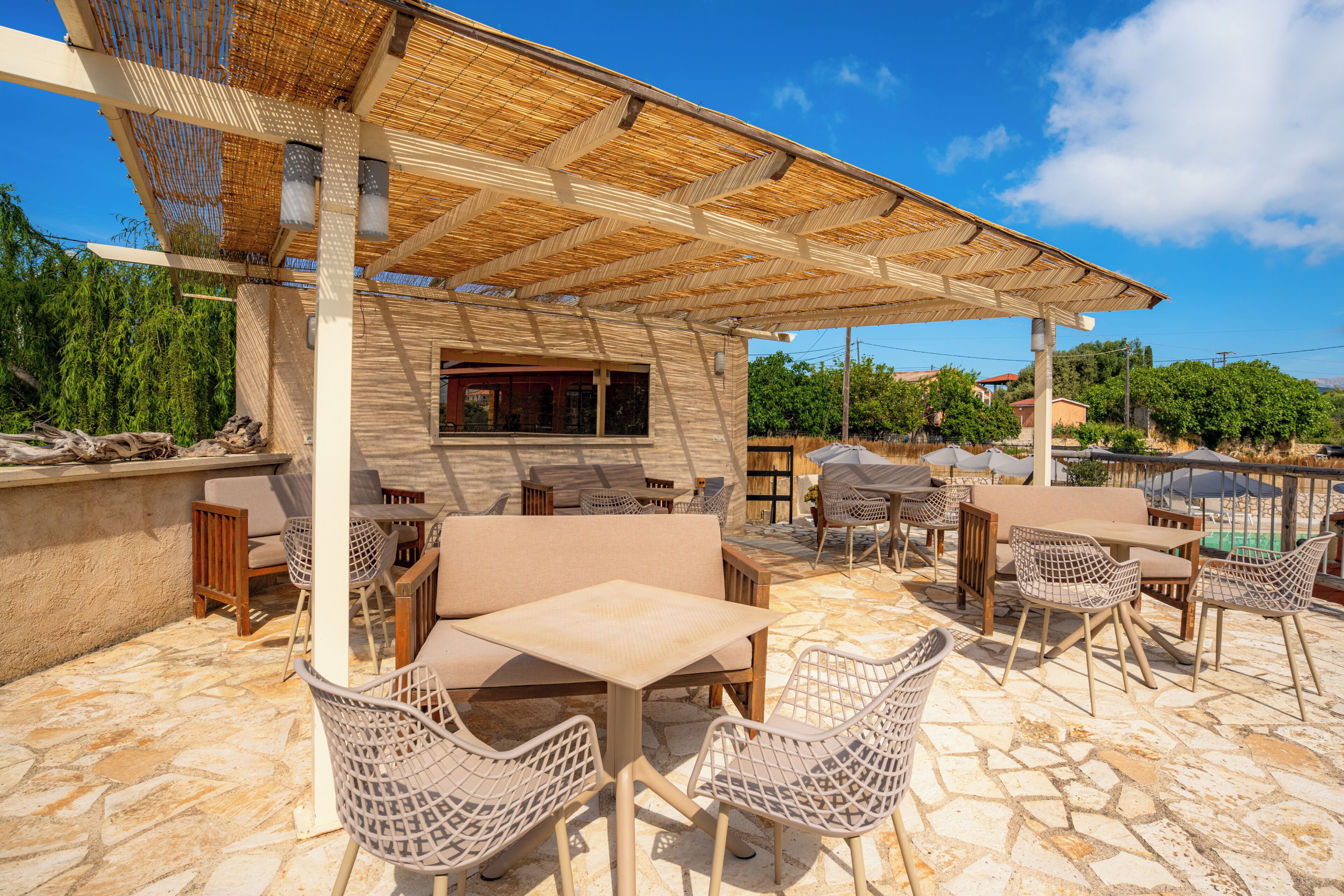 An outdoor patio with stone flooring, wicker furniture, and a covered seating area.