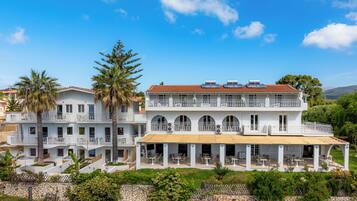 Un edificio a due piani con balconi, un portico coperto e un muro in pietra.