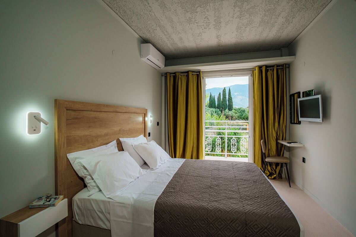 A hotel room with a bed, a TV mounted on the wall, and a window with curtains.