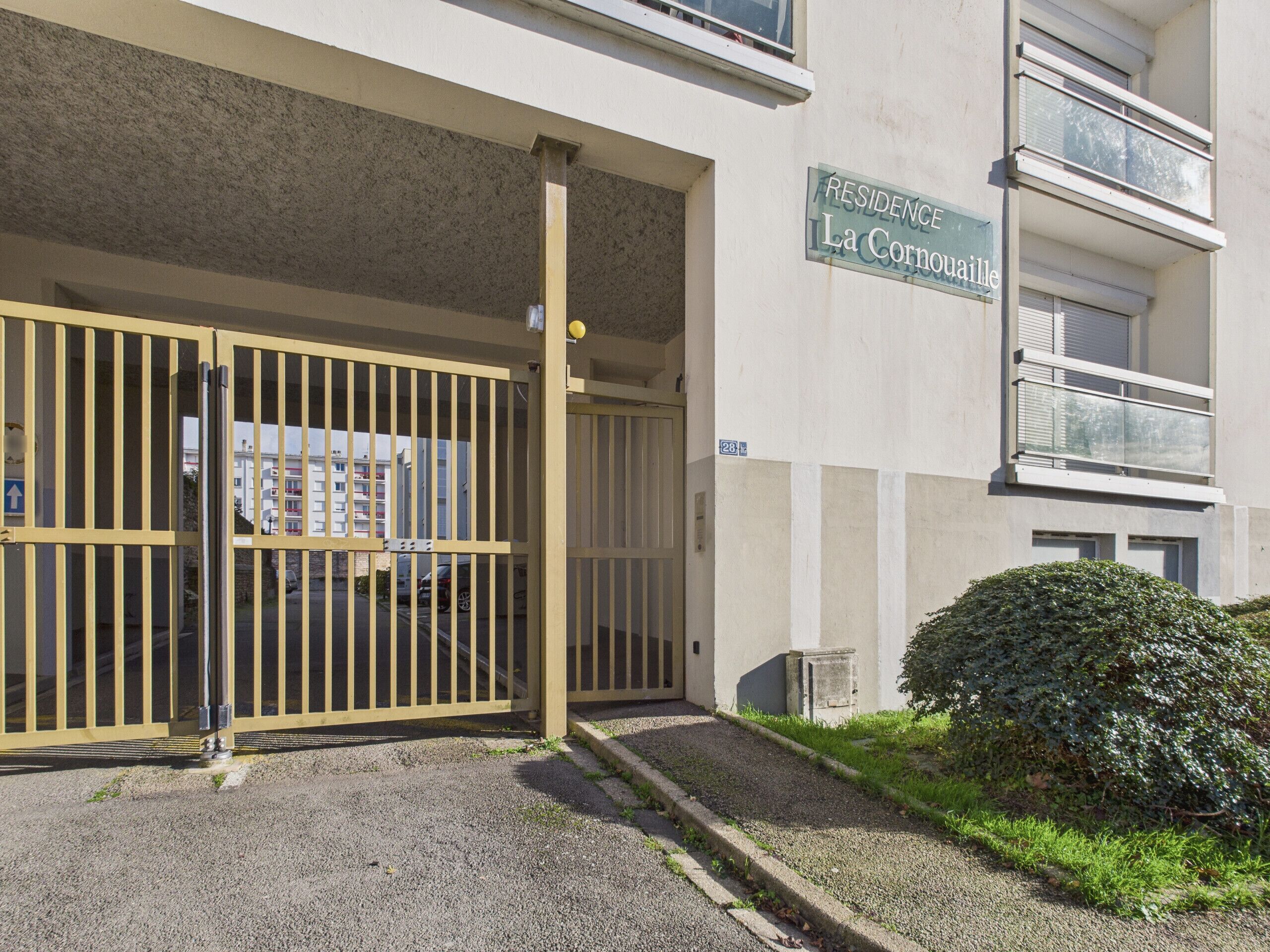 Un cancello conduce all'ingresso di un edificio con un'insegna che riporta la scritta "RESIDENCE La Cornouaille".