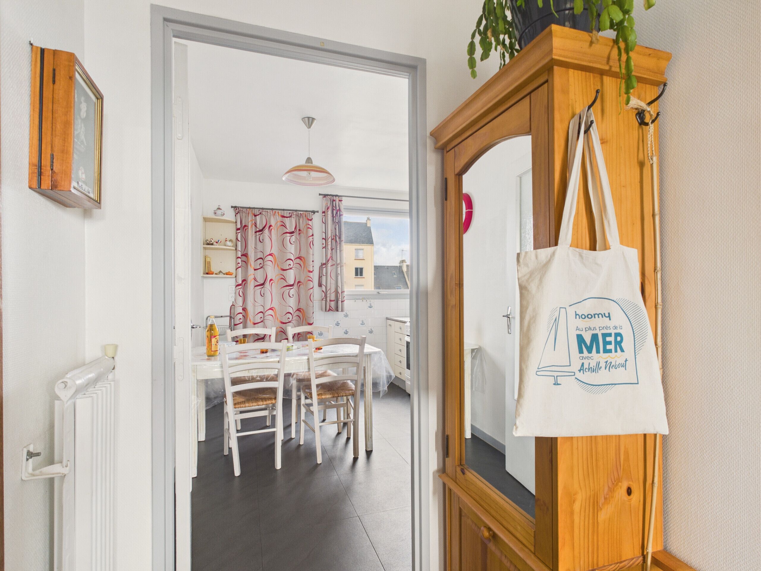 Une cuisine moderne avec des meubles blancs, une table à manger avec des chaises et une vue sur l’extérieur.