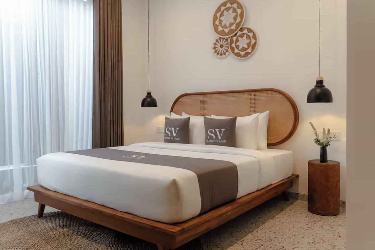 A neatly made bed with a headboard, two bedside lamps, and a decorative wall piece above it.