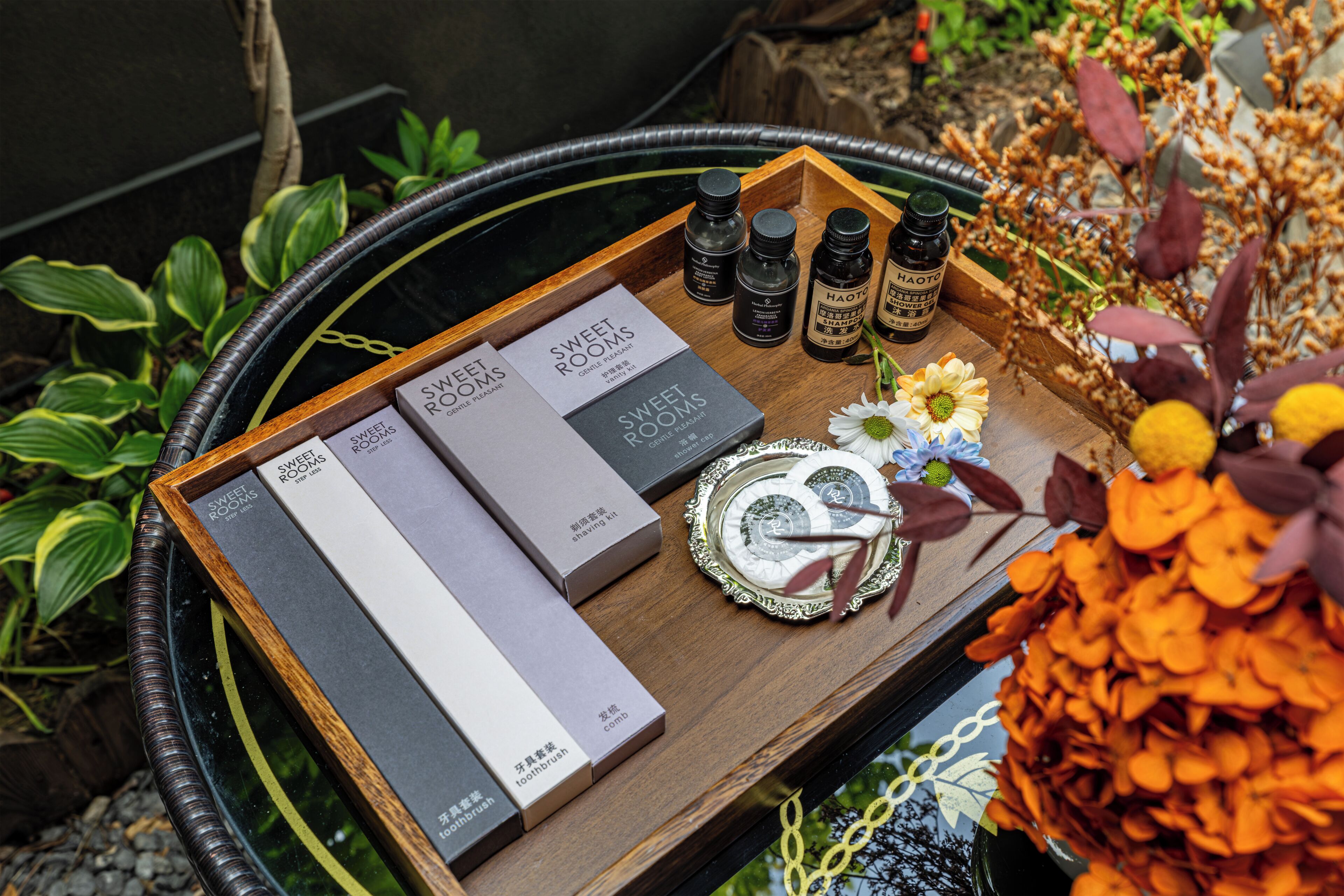 Una bandeja con cajas etiquetadas 'Sweet Rooms' y 'Haotic', junto con botellas y un plato decorativo.