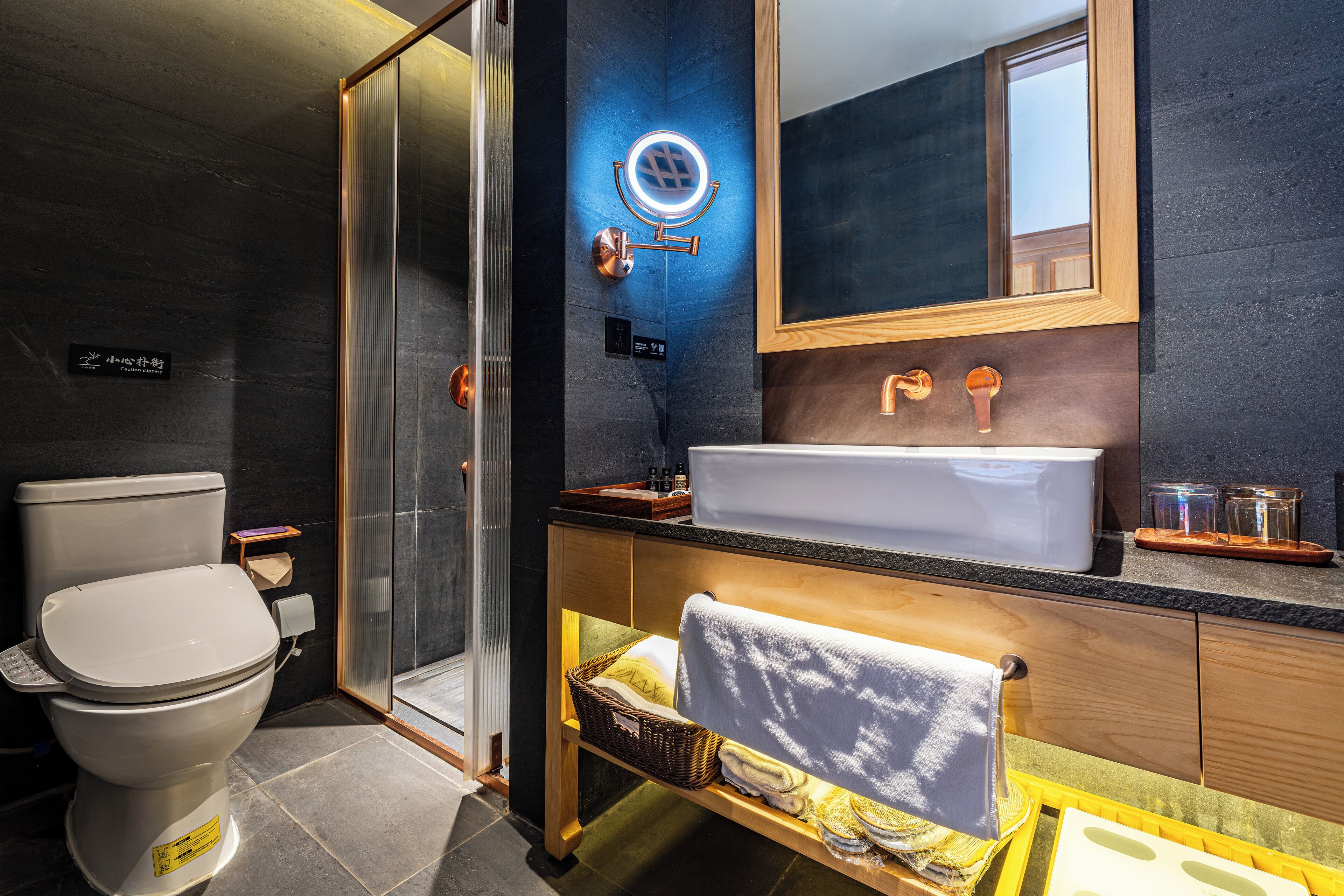 A modern bathroom with a toilet, shower, sink, and a mirror above the sink.