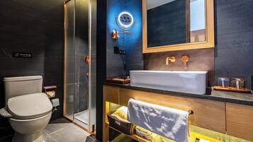 A modern bathroom with a toilet, shower, sink, and a mirror above the sink.