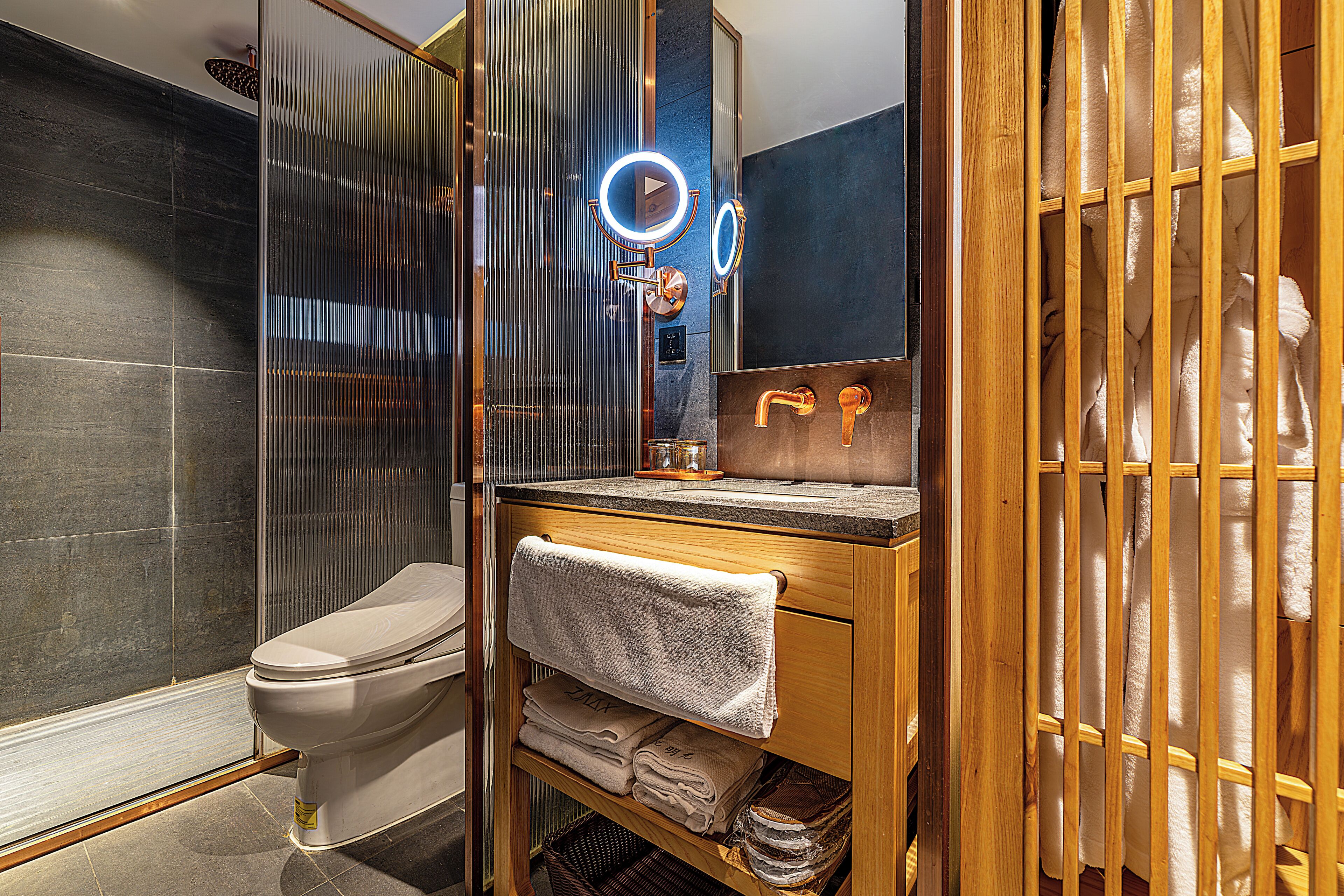 Une salle de bain comprenant des toilettes, un meuble-lavabo avec un miroir et un espace douche.
