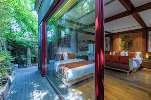 A modern bedroom with a large bed, a wooden floor, and a view of a garden through a glass wall. - The JOY courtyard Beijing near Tiananmen Forbidden City (Beijing)