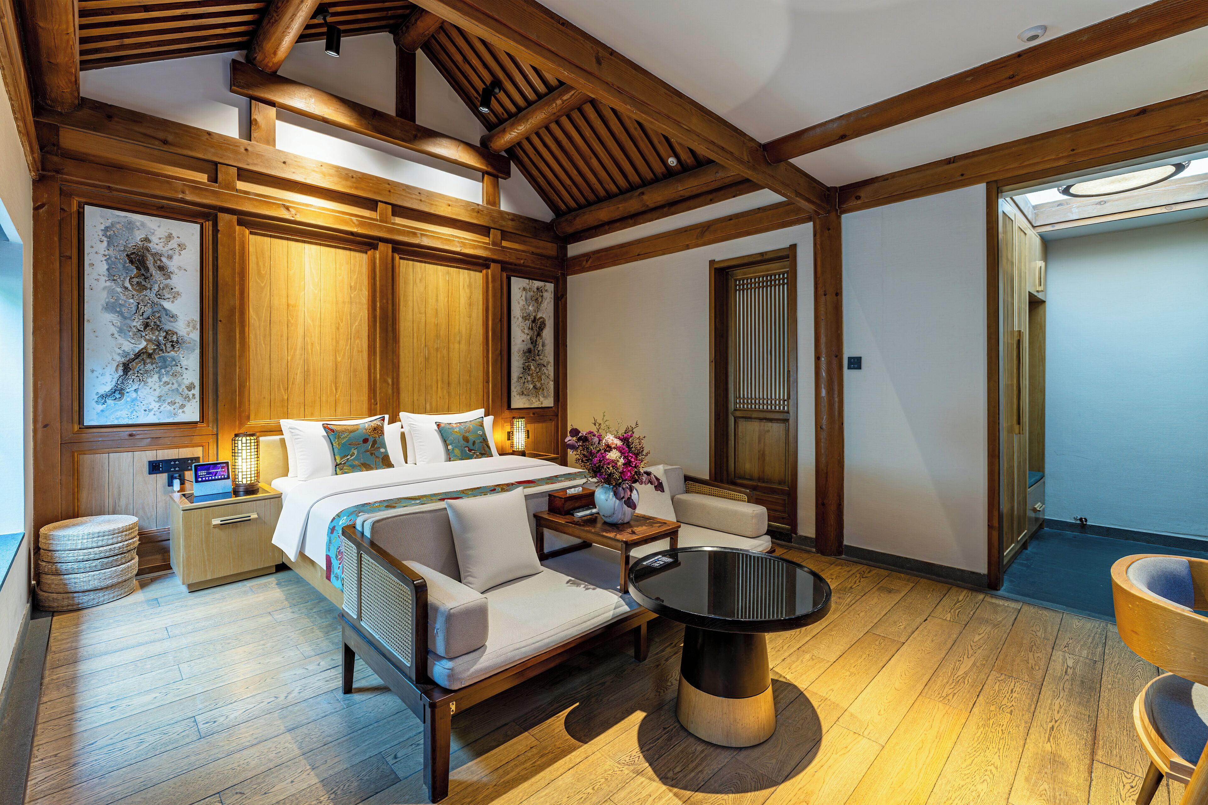 Ein Hotelzimmer mit Bett, Sofa, rundem Tisch und Holzbalken.