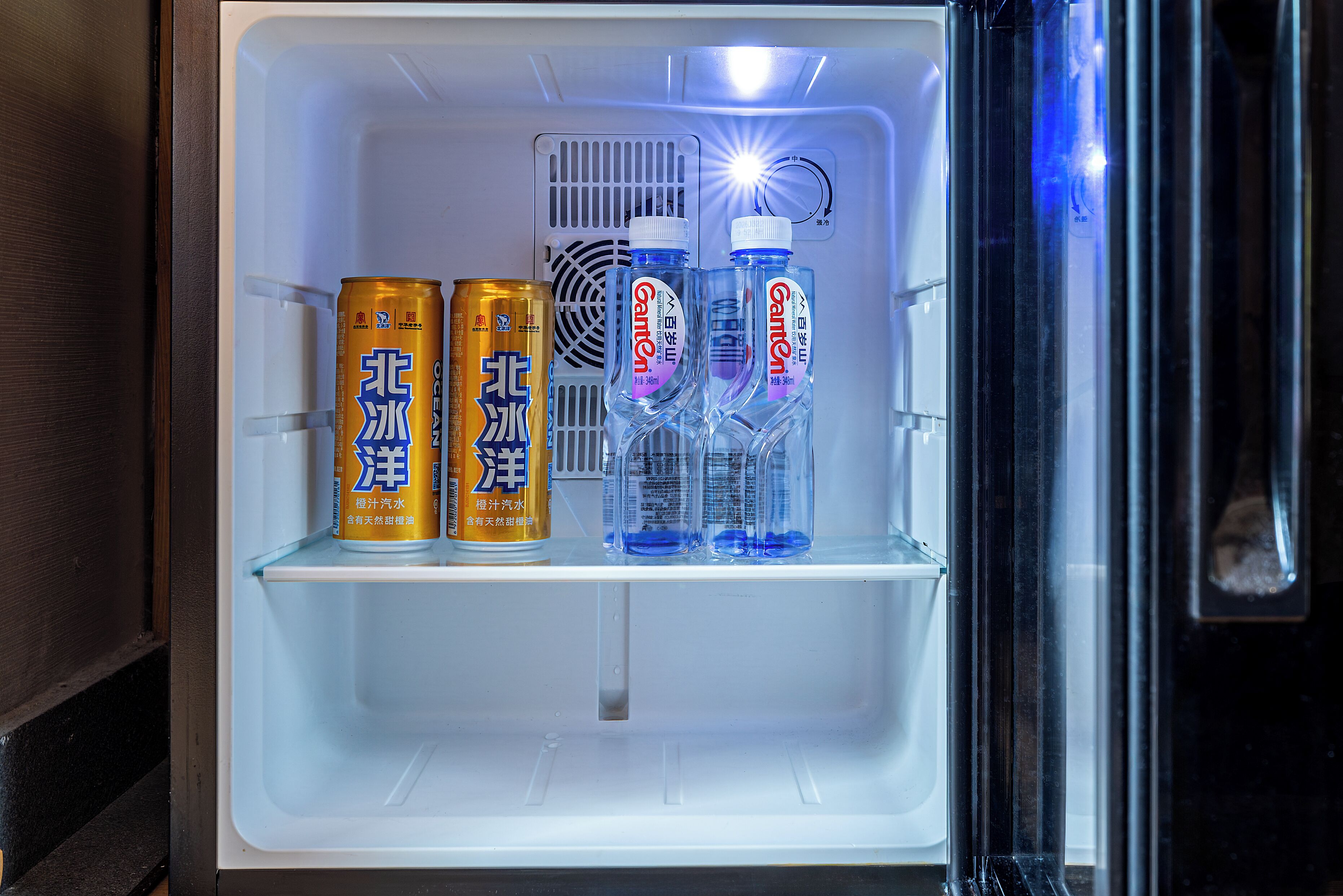 Un refrigerador con bebidas y un ventilador.