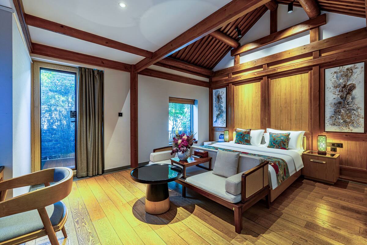 A room with a bed, a sofa, a dining table, and a chair.