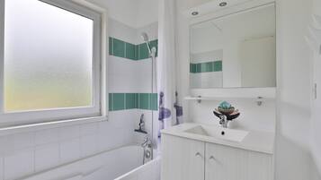 Een moderne badkamer met een bad, een douche, een wastafel en een spiegel.