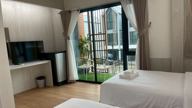 Een hotelkamer met twee bedden, een televisie, een klein tafeltje en een balkon met uitzicht op de stad.