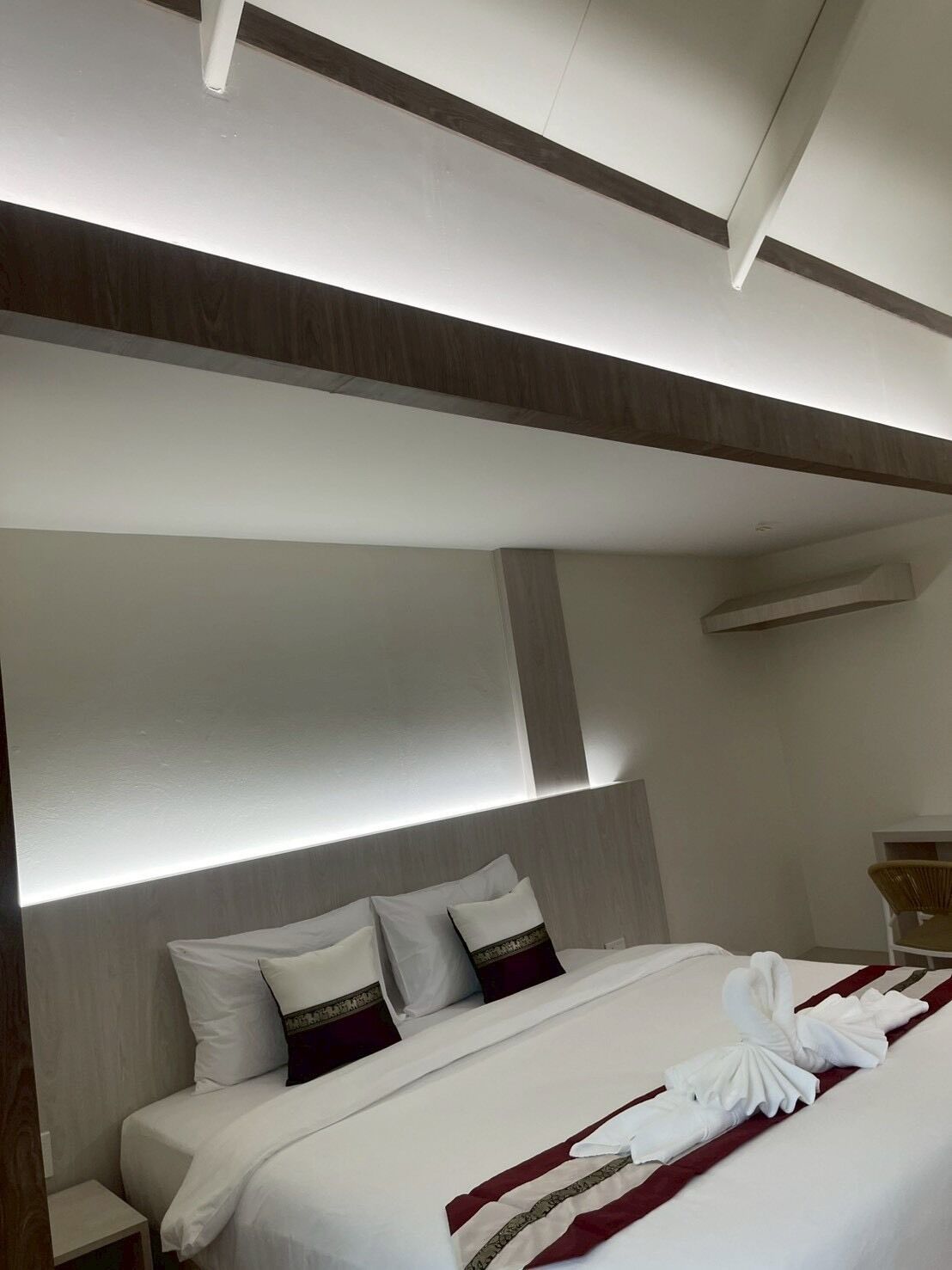 Ein modernes Hotelzimmer mit einem großen Bett, weißen Handtüchern und ordentlich drapierten Handtüchern.