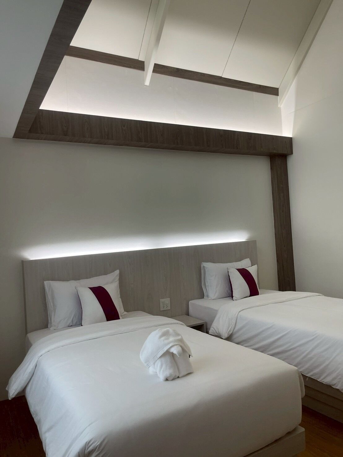 Een hotelkamer met twee bedden, een houten plafond en een modern design.