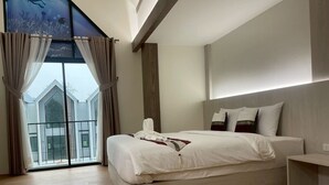 Een moderne hotelkamer met een groot bed, uitzicht op een gebouw door een raam, en een balkon met gordijnen.