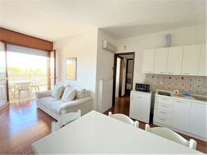 A compact living space with a balcony, a kitchenette, and a dining area. - Bibione Apartment With sea View (San Michele al Tagliamento)