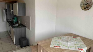 Una cocina con electrodomésticos modernos, una mesa de comedor con mantel estampado y un reloj de pared.