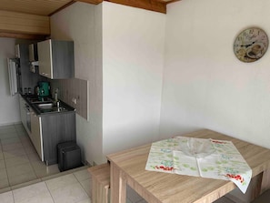 Una cocina con electrodomésticos modernos, una mesa de comedor con mantel estampado y un reloj de pared.