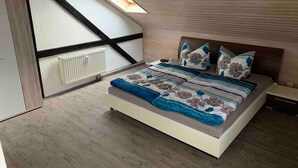 Un dormitorio con techo inclinado, tragaluces, cama con ropa de cama floral y radiador.
