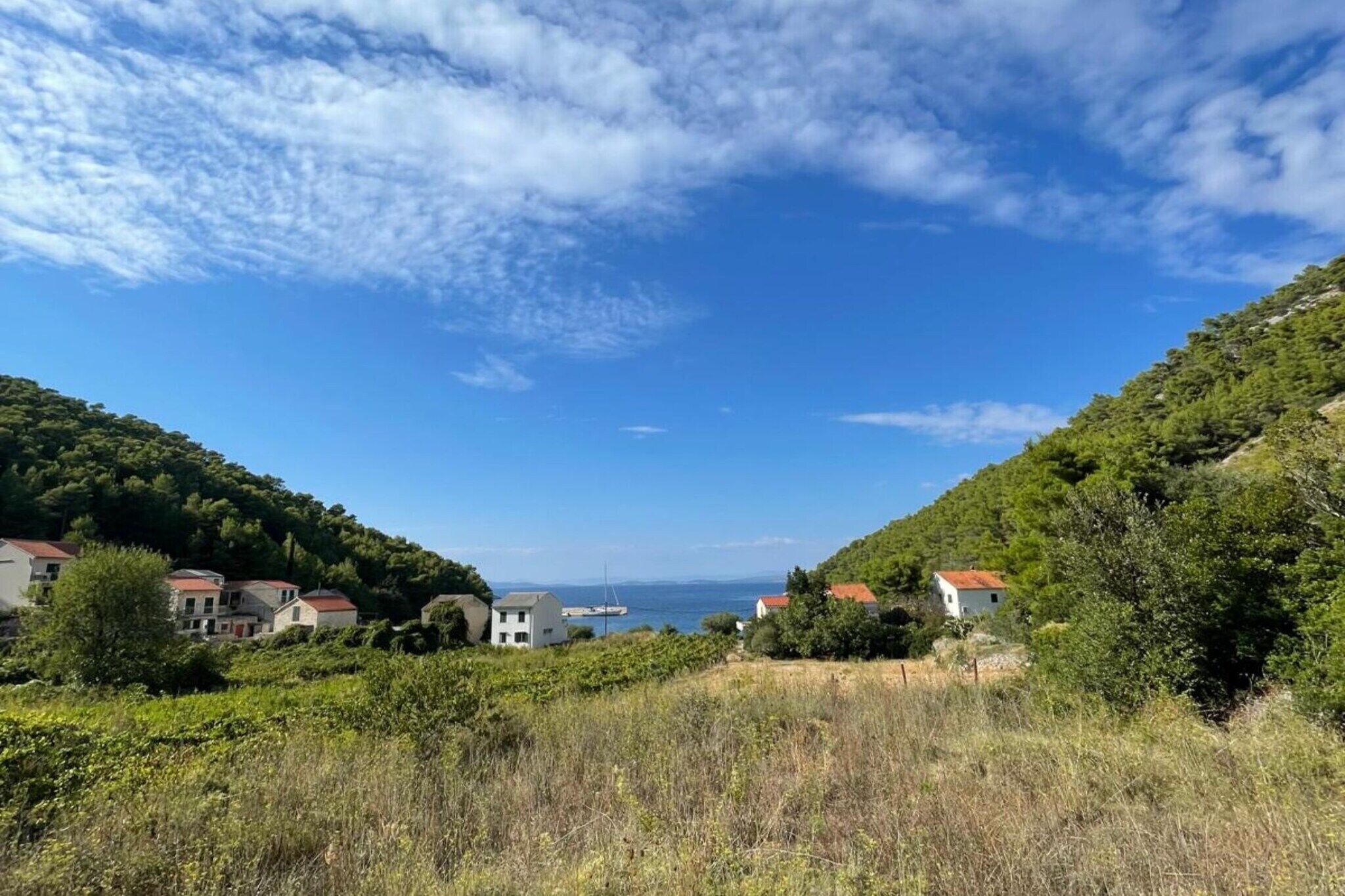 A coastal village with houses on hills, a clear sky, and a view of the sea.