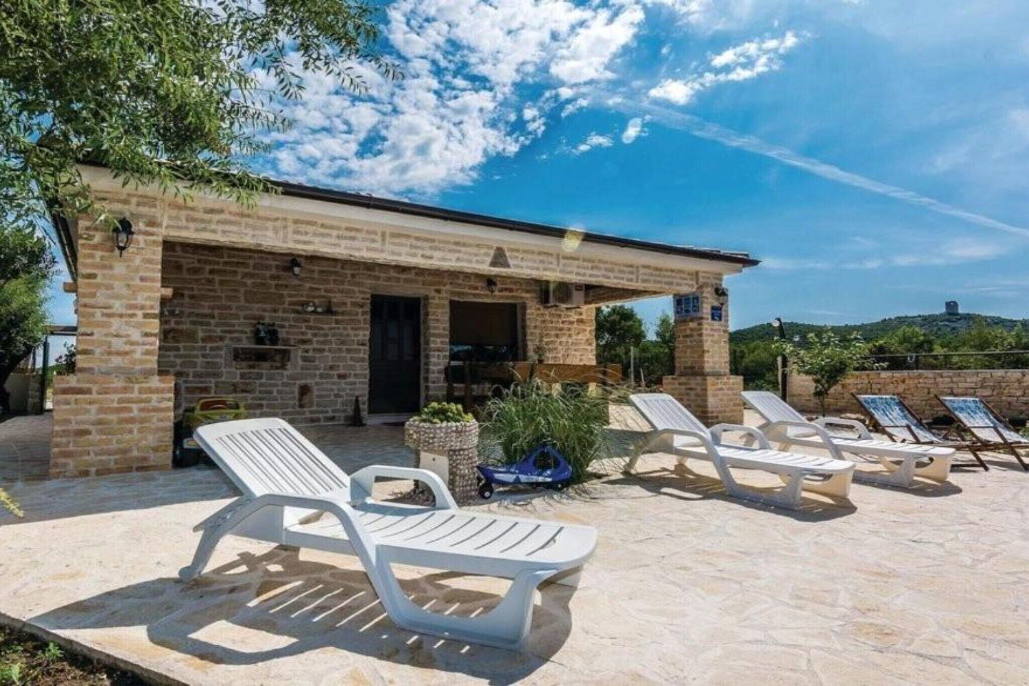 A brick building with a covered patio area featuring white lounge chairs.