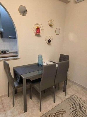 Een eethoek met een tafel, stoelen, een raam en decoratieve wandlampen.