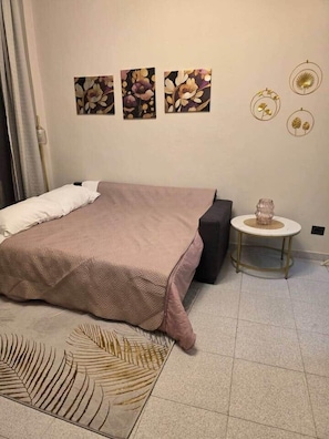 Een slaapkamer met een bed, een rond tafel en drie kunstwerken aan de muur.