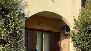 A building with a glass door entrance, a small covered porch, and a wall-mounted air conditioning unit. - Roma 1 Apartment - THE V Collection (Turate)