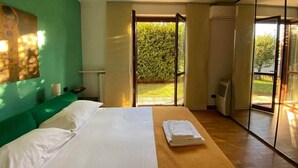 A modern bedroom with a bed, a green wall, a large window, and a view of greenery outside. - Roma 1 Apartment - THE V Collection (Turate)